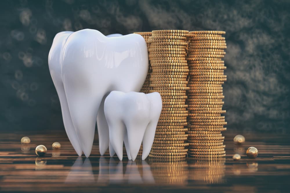 Model teeth standing beside tall stacks of gold coins